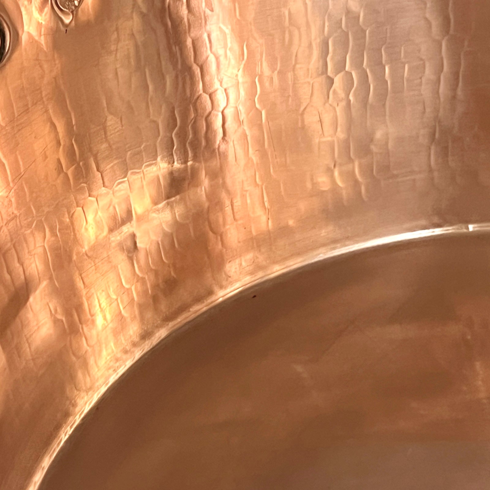 Close-up of copper sink with brass pop up waste on a white background