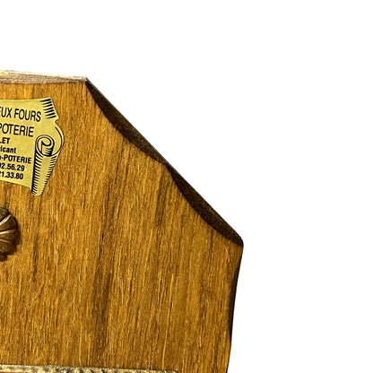 Close-up of a wooden and copper key holder with a yellow paper label reading 'LUX FOURS POTERIE' on a plain white background.