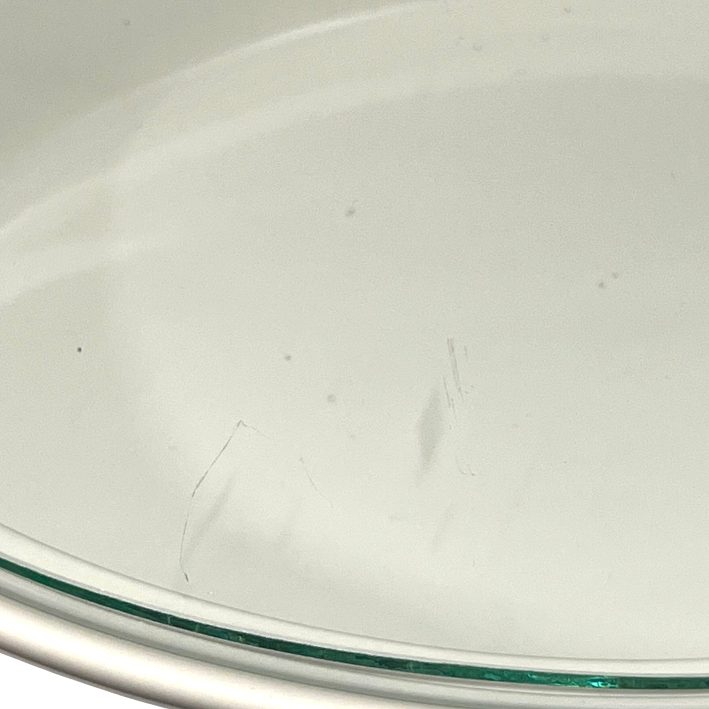 Close-up of a glass plate with a slight scratch on a white background