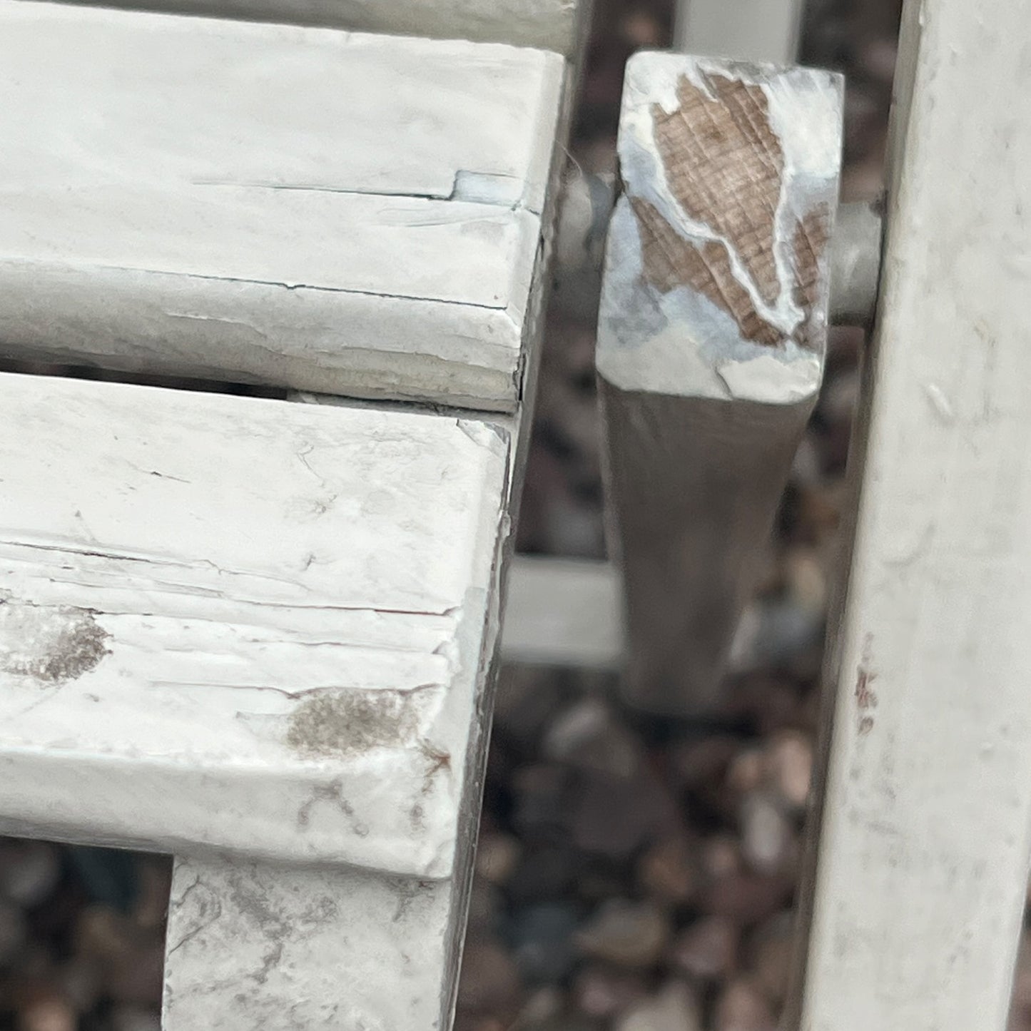 A close-up view of a painted wooden slatted garden chair set amidst a lush garden backdrop.