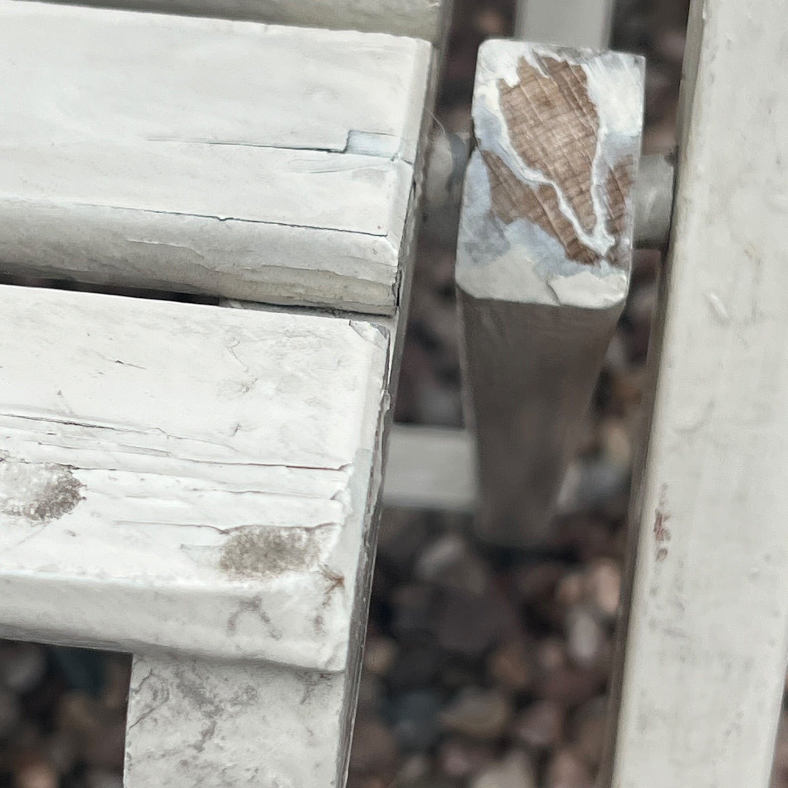 A close-up view of a painted wooden slatted garden chair set amidst a lush garden backdrop.