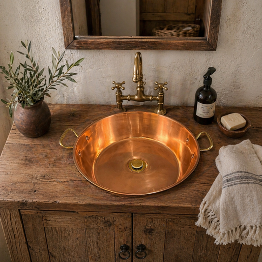 Copper sink with brass handles and a brass pop up waste on a wooden vanity with a rustic setting, ideal for a quirky bathroom design or rustic style bathroom