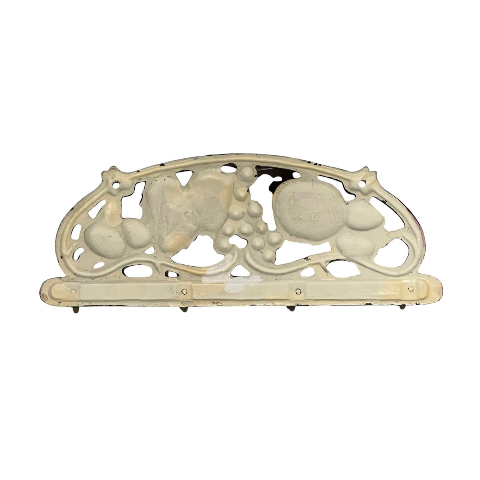 An ornate vintage metal wall plate or bracket with a decorative scrollwork design featuring grape and leaf motifs, finished in an aged cream or off-white color.