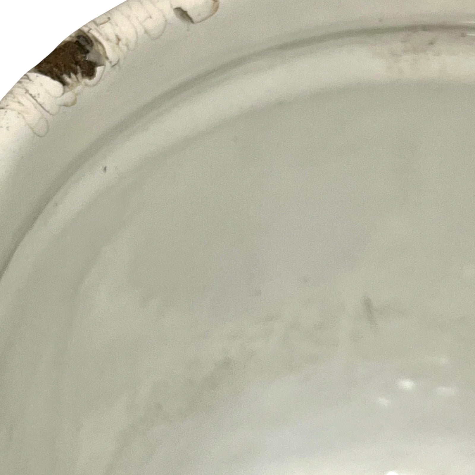 Close-up of a white enamel jug showing the interior surface and a chipped edge with some discoloration.