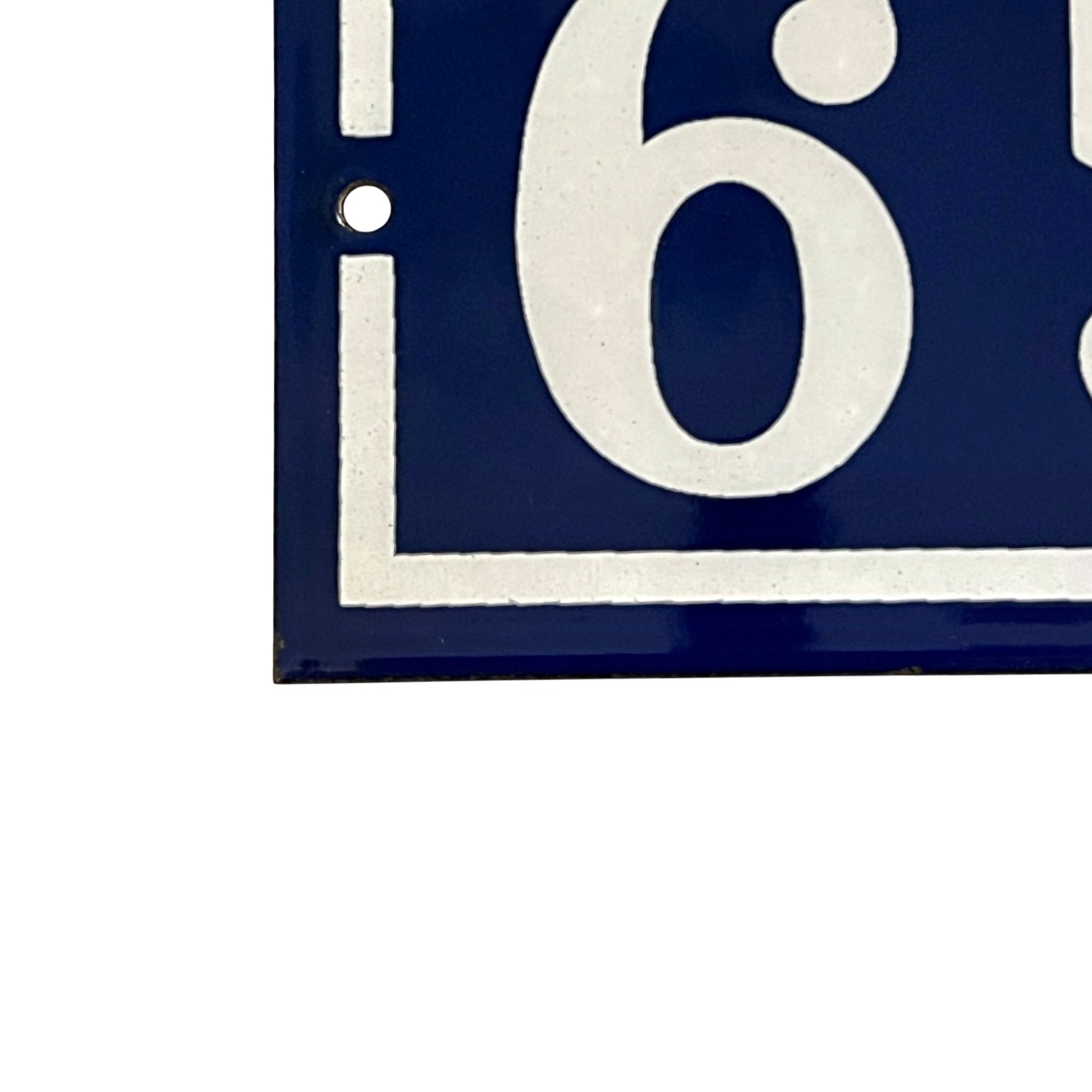 Close up of blue and white door number 65 on a white background 