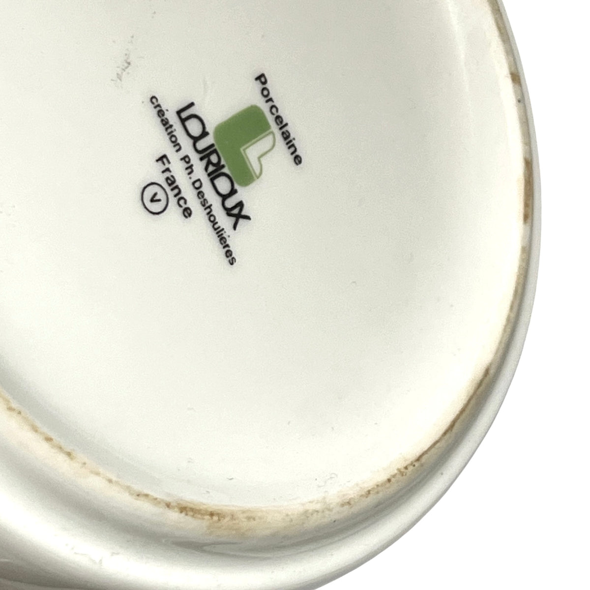 Close-up of the inside bottom of a white porcelain dish or cup, showing the LOUBOUX brand mark with a green logo and text on a white background.