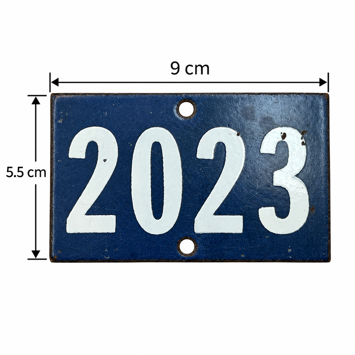 A rectangular dark blue metal house number plaque with the year '2023' in large white numerals, shown with dimension annotations indicating 9 cm width and 5.5 cm height.