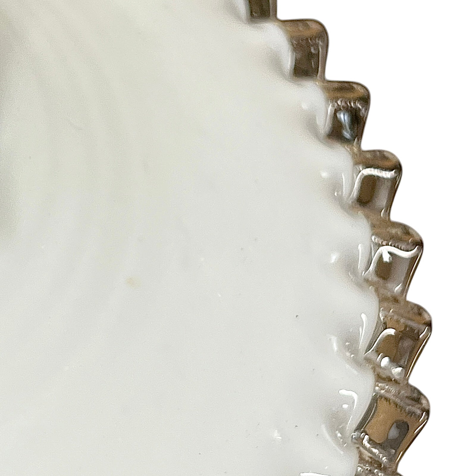 Close-up of a white glass lampshade with decorative edge on a white background