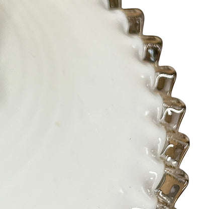 Close-up of a white glass lampshade with decorative edge on a white background