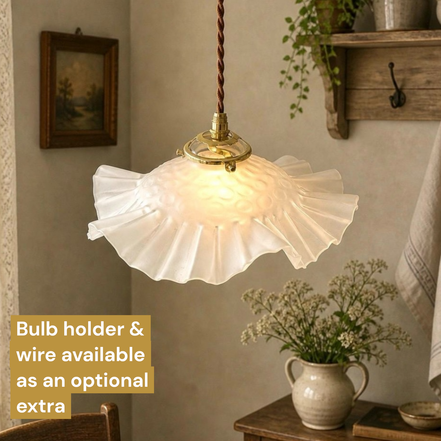 A ruffled white glass pendant light with a brass fixture and twisted brown cord, shown hanging in a styled interior room. A text box in the lower left says 'Bulb holder & wire available as an optional extra'.