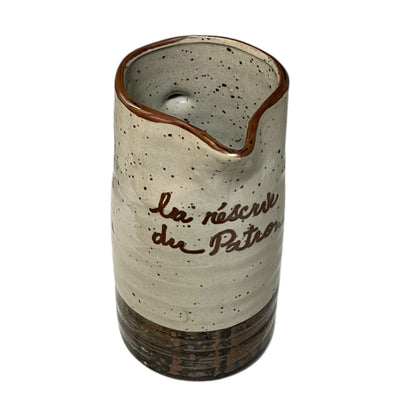 Ceramic speckled brown and cream vase with French text on a white background
