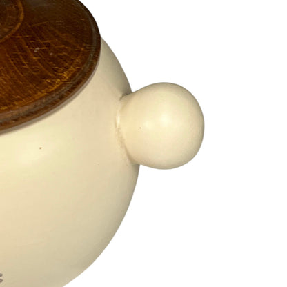 Close-up of a ceramic pot with a wooden lid on a white background