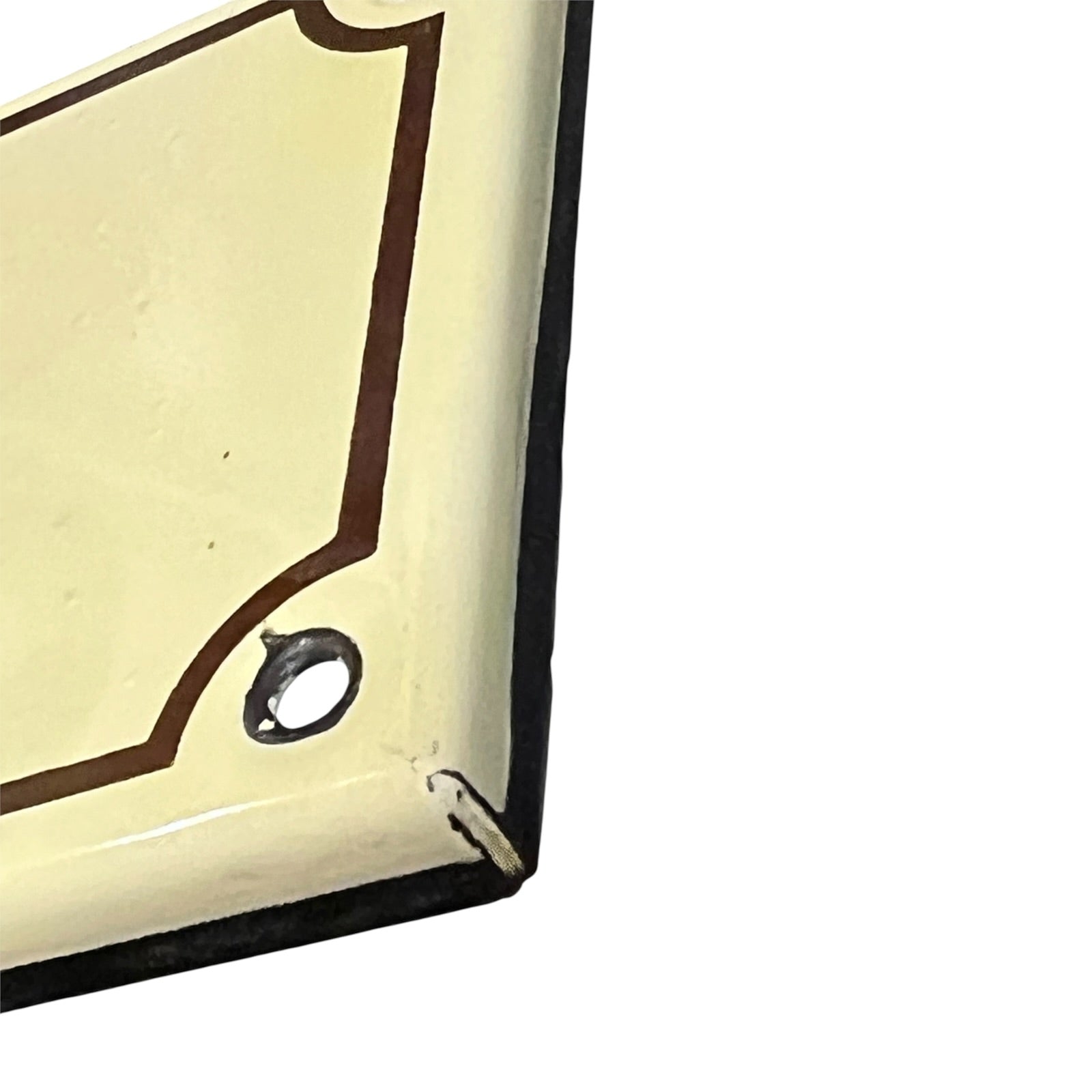 Close-up of a cream-colored enamel wall sign with a dark brown border and a metal mounting hole, showing some wear and damage on a white background.