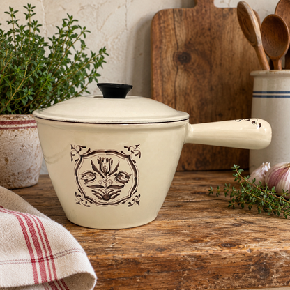 French vintage Le Creuset pan with a lid and a tulip pattern on a wood table with a cloth