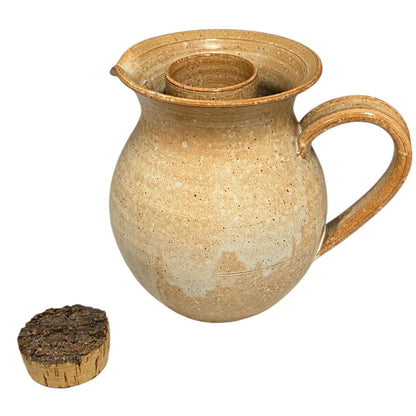 Stoneware pitcher with a small wooden block on a white background