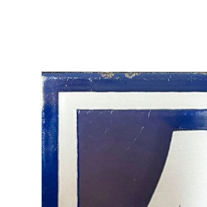corner view of a vintage French enamel door number against a white background.