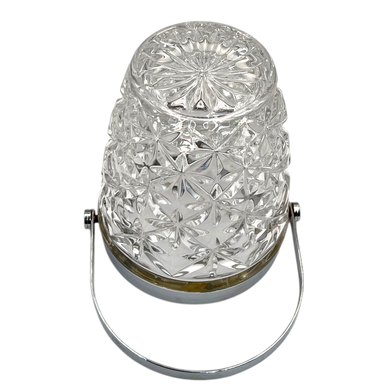 Close up of French cut glass ice bucket with textured design and metal handle on a white background 