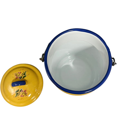 A yellow enamel storage container with a blue rim and floral decoration on the lid, shown open with the lid placed beside it on a white background.