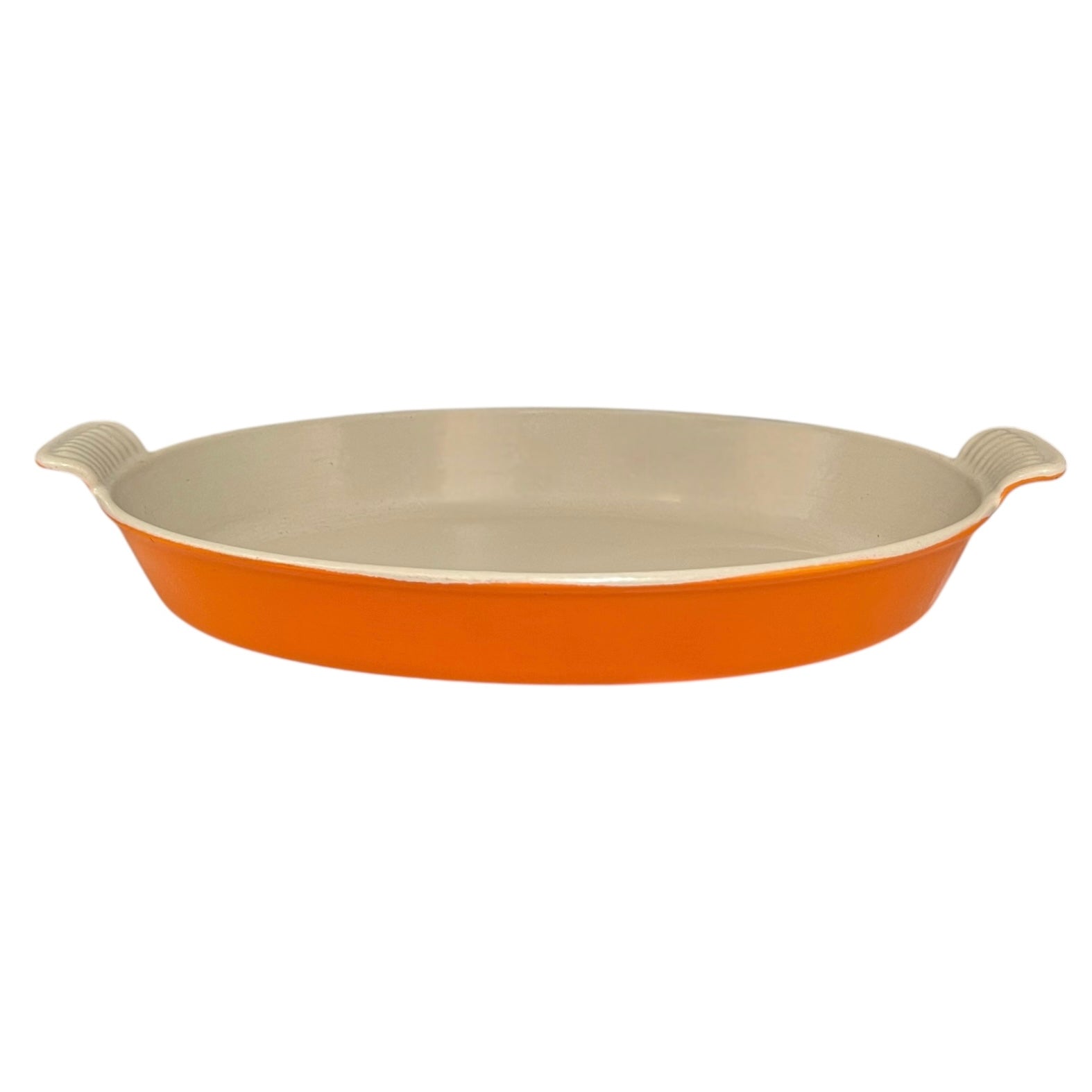 French orange Le Creuset dish with beige interior on a white background