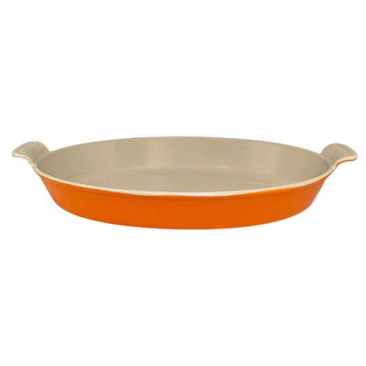 French orange Le Creuset dish with beige interior on a white background