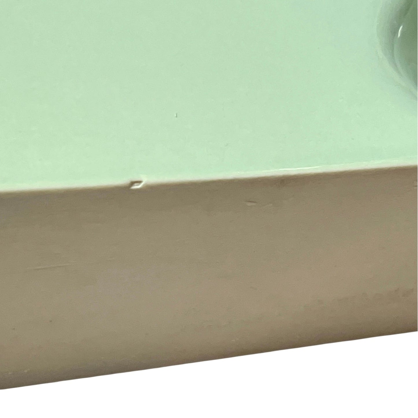 back view of pale green ceramic shelf on a white background