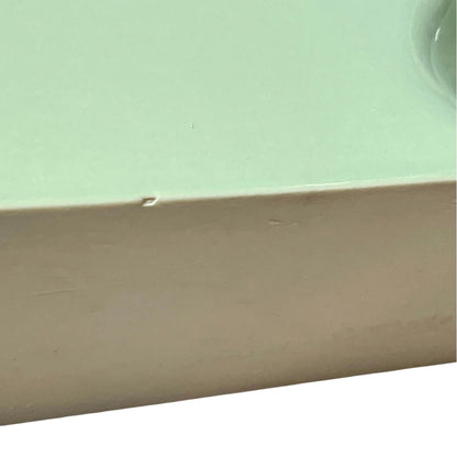 back view of pale green ceramic shelf on a white background
