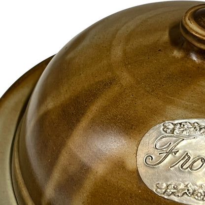 Close-up of a brown ceramic pot with a visible fromage label on a white background