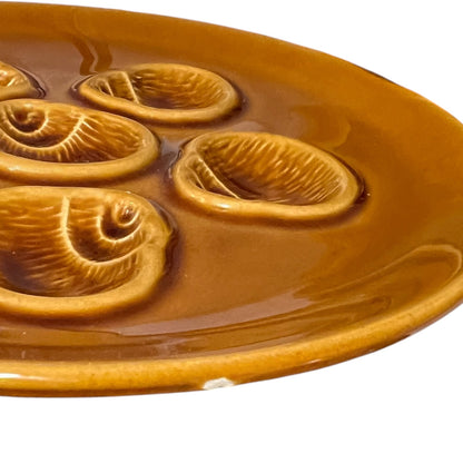 Brown ceramic plate with shell designs on a white background