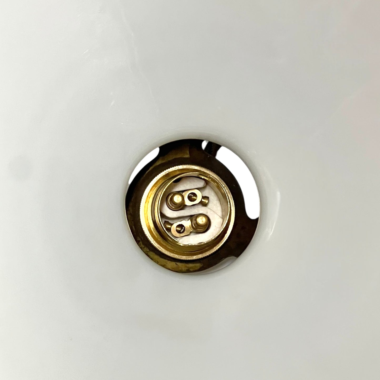 close up of brass ceiling light fixture with white glass shade on a white background