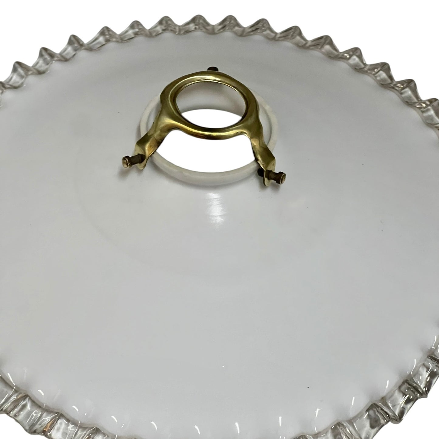 Clear glass lamp shade with a gold metal clip on a white background