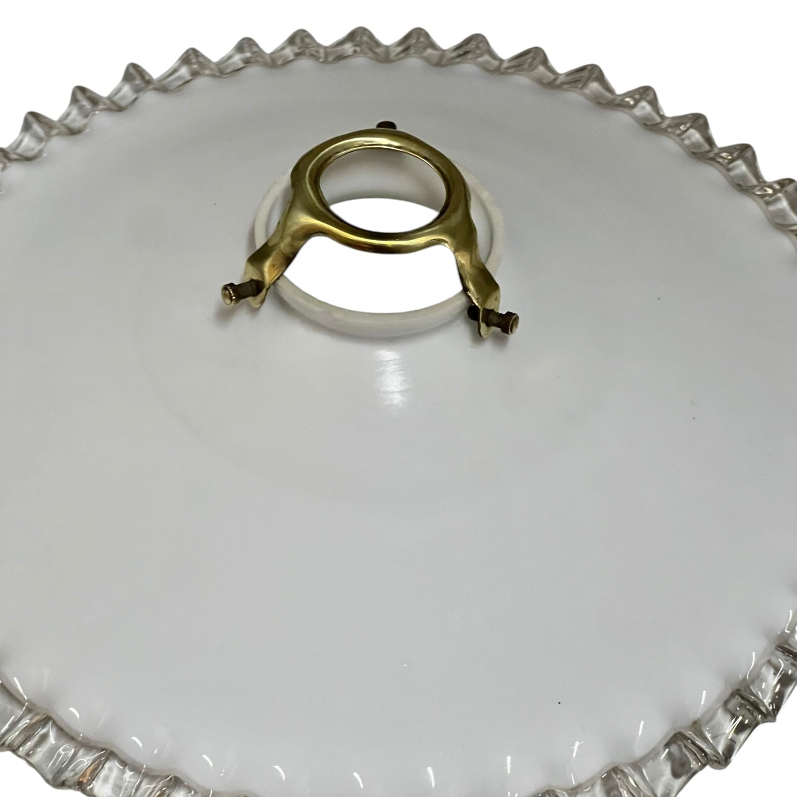 Clear glass lamp shade with a gold metal clip on a white background