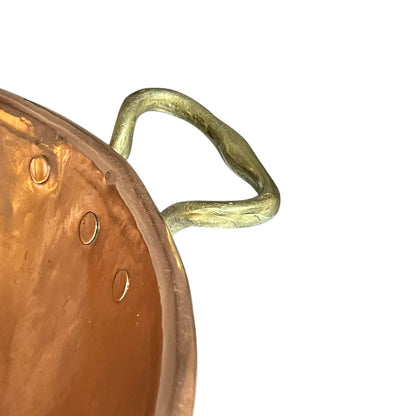 Close-up of a copper pot with a brass handle on a white background