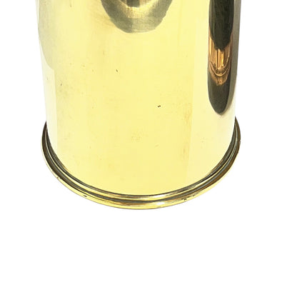 Close-up of the bottom of a shiny brass or gold-toned metal container or vessel on a plain white background.