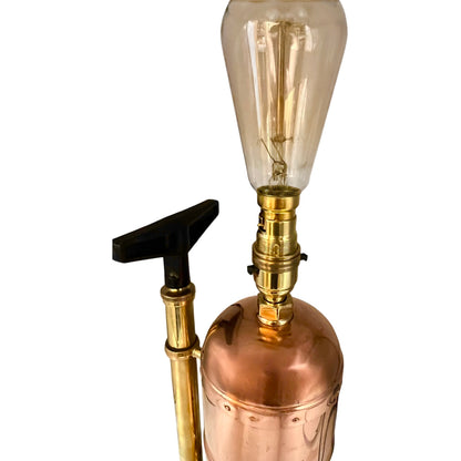 Vintage-style copper and brass lamp with a clear glass bulb on a white background