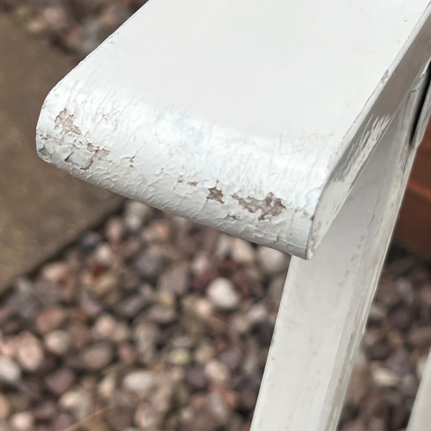 A close-up view of a painted wooden slatted garden chair set amidst a lush garden backdrop.