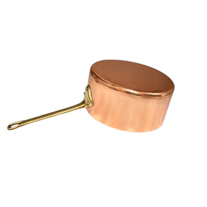A copper saucepan with a long brass handle, shown from a side angle against a plain white background.