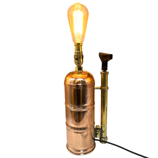 Vintage-style brass and copper lamp with a lit bulb on a white background