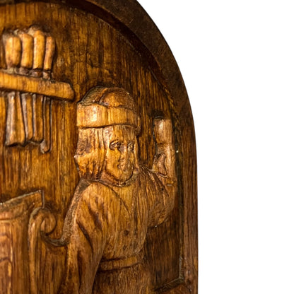 Wooden carving of a person with a hat and a book, on a white background