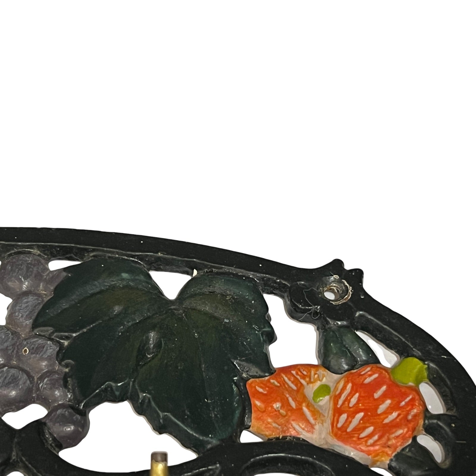 Close-up of a decorative cast iron hook set or stand featuring a black metal frame with embossed grape leaves and orange-red grapes, shown against a plain white background.