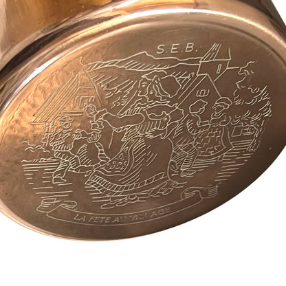 Close-up of a decorative metal object with engraved design and 'S.E.B.' inscription.