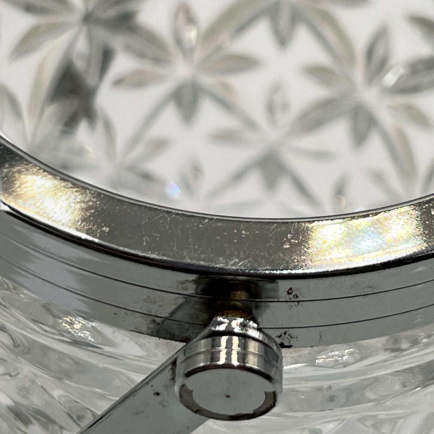 Close up of French cut glass ice bucket with textured design and metal handle on a white background 