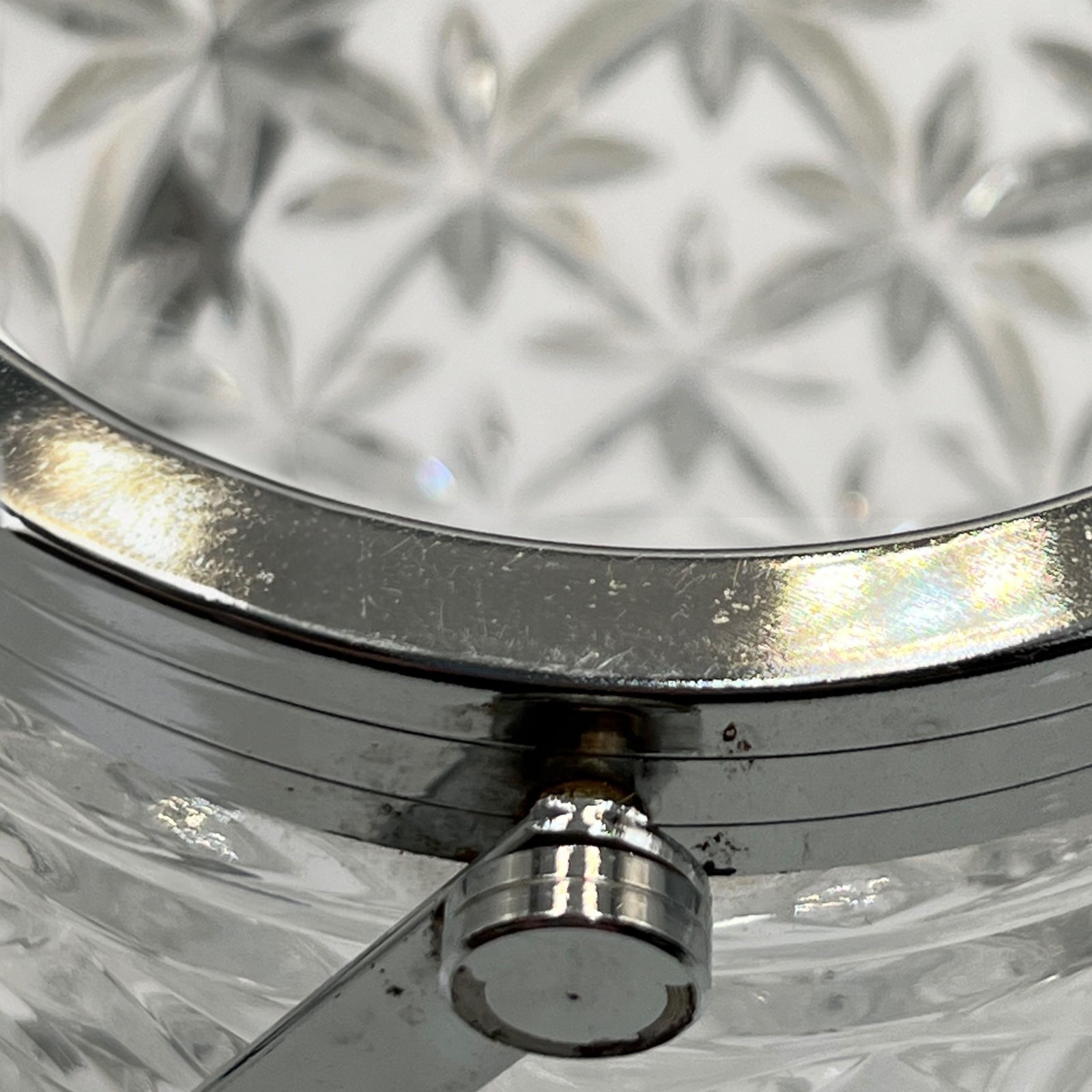 Close up of French cut glass ice bucket with textured design and metal handle on a white background 