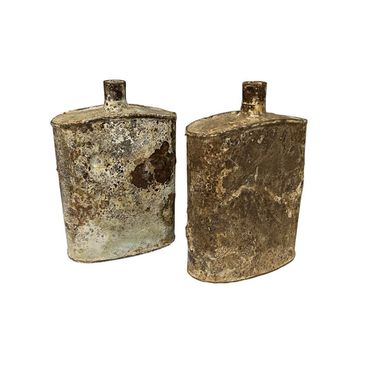 Pair of relic British WW1 metal water bottles in a rusty and flaky condition on a white background