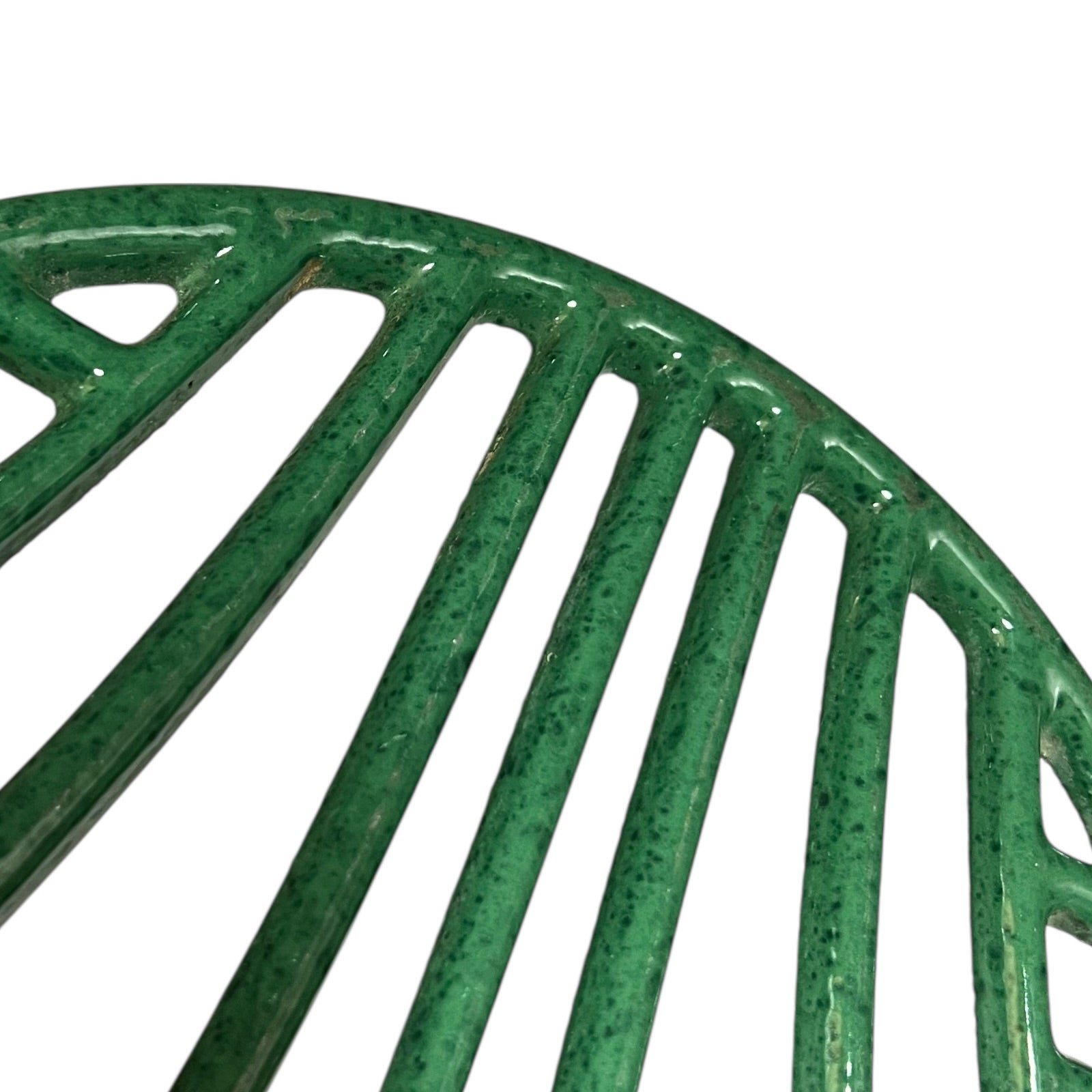 Close up of a green vintage French cast iron enamelled pan trivet on a white background