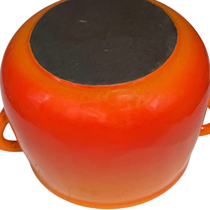 An orange ceramic pot with side handles, shown from a top-down angle against a white background.