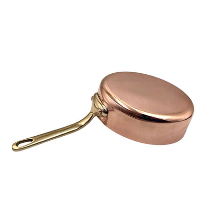 Copper frying pan with a brass handle on a white background