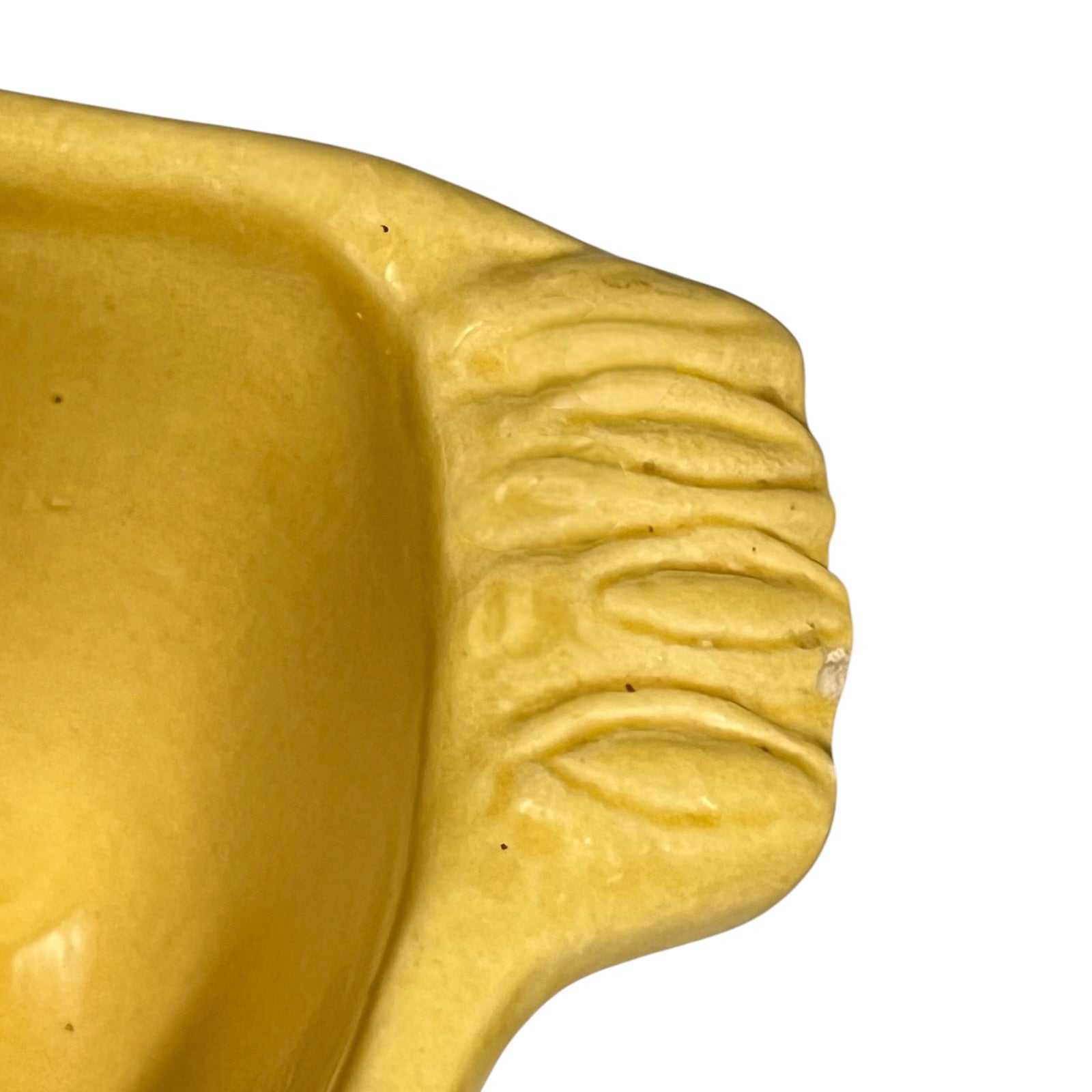 Close-up of a yellow bowl, showing a ribbed textured section on the right side against a plain white background.