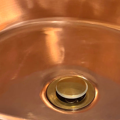 Close-up of a copper sink with a brass drain