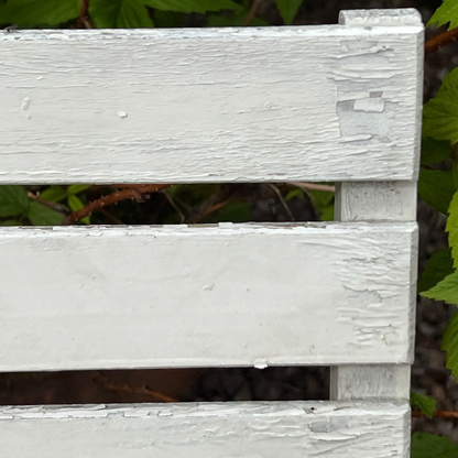 Close-up detail of French wooden slatted chairs, highlighting their condition in an outdoor setting.