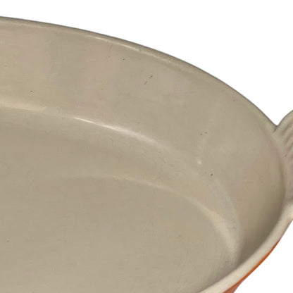 Close up of Le Creuset dish with beige interior on a white background